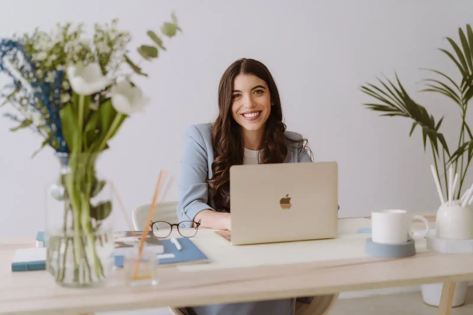 Silvia Nieto, editora y formadora, sonriendo en su escritorio con portátil y flores