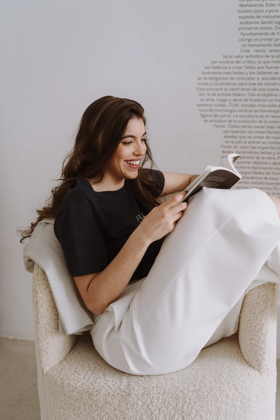 Silvia Nieto leyendo un libro en un sillón, rodeada de palabras