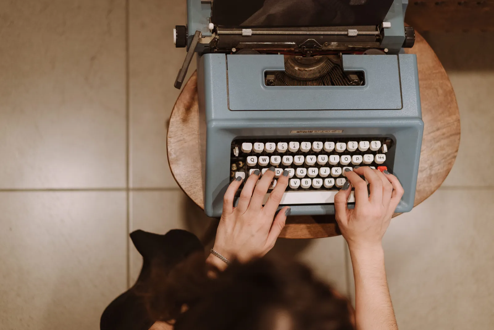 Manos escribiendo en una máquina de escribir azul: traducción literaria de libros